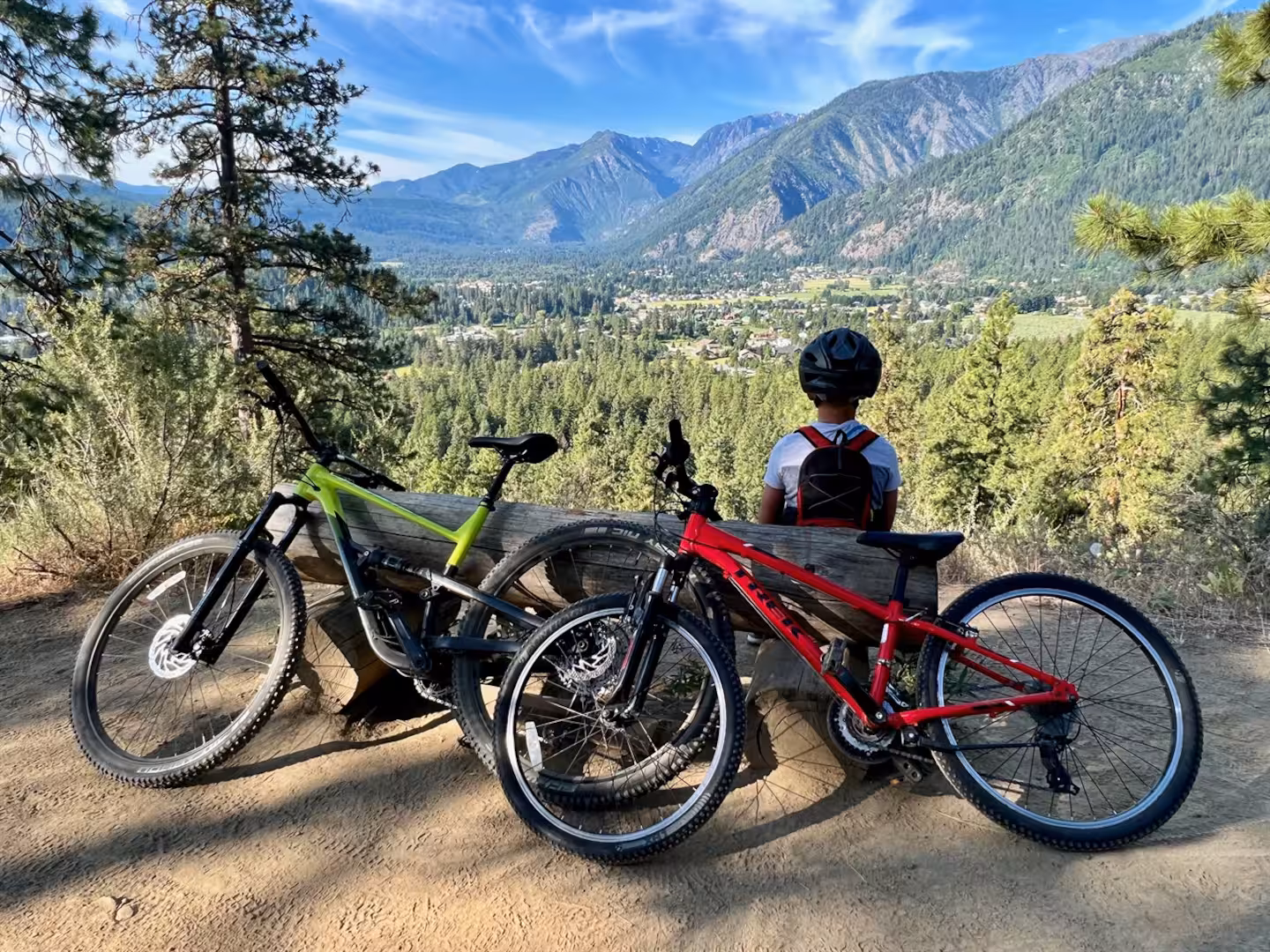 Two mountain bikes at a log bench on a ridge trail overlooking the Leavenworth valley