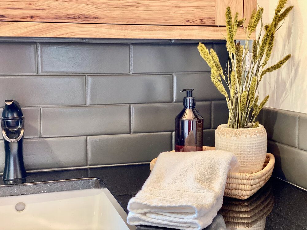 Black granite vanity with a grey tiled backsplash, folded towels and soap in the bathroom at The Cascade Chalet