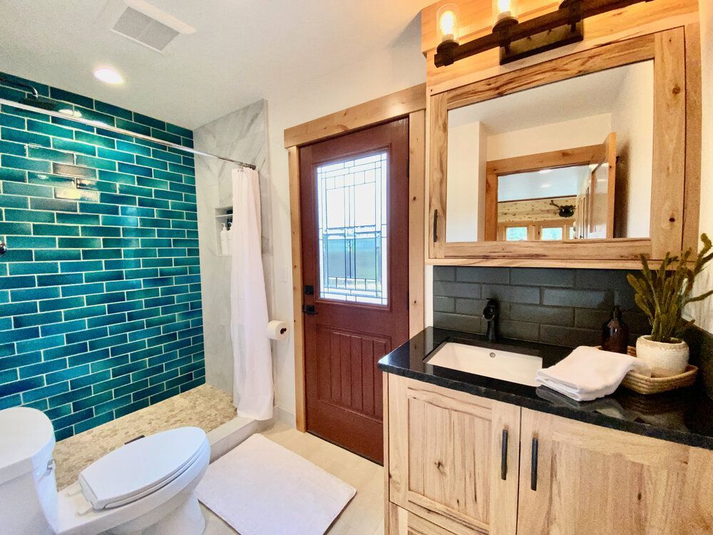 Bathroom with a teal tiled shower and custom vanity