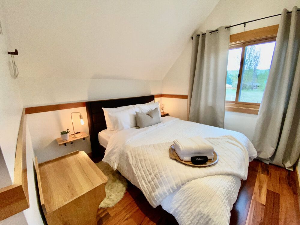 Third bedroom upstairs with a queen bed under a sloped ceiling and a window