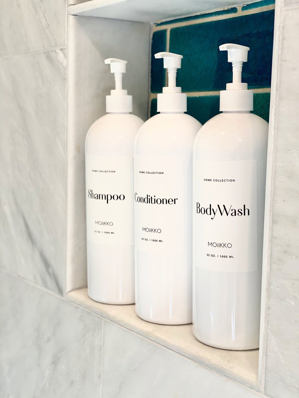Shampoo, conditioner and body wash in refillable bottles in the marble shower niche