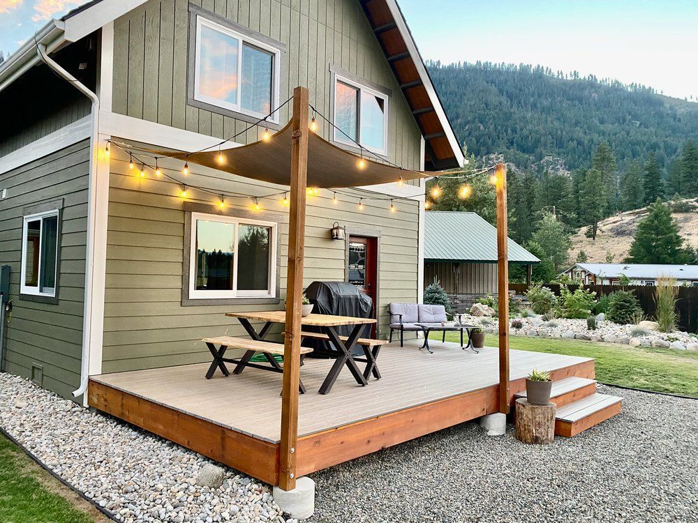Covered patio with string lights, picnic table and mountain views at The Cascade Chalet