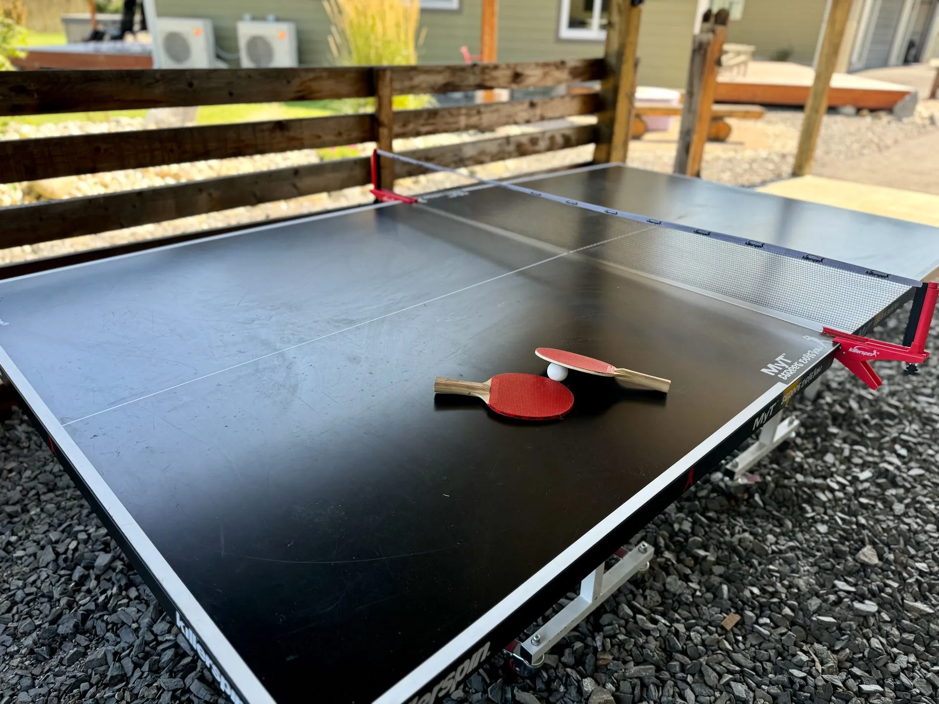 Outdoor ping pong table with paddles and a ball set up beside the hot tub at The Cascade Chalet